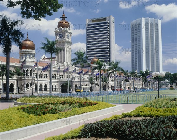 MALAYSIA, Peninsular, Kuala Lumpur, Sultan Abdul Samad building with its copper domes and skyscrapers beyond  with flower beds in the foreground