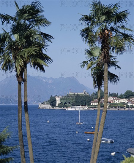 ITALY, Piedmont, Lake Maggiore, View through to palms on Stresa waterfront across the lake towards Isola Bella Island