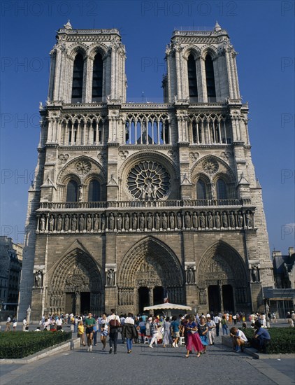 FRANCE, Ile de France , Paris, "Cathédrale de Notre Dame.  Gothic exterior with twin towers and rose window, crowds of visitors outside entrance."