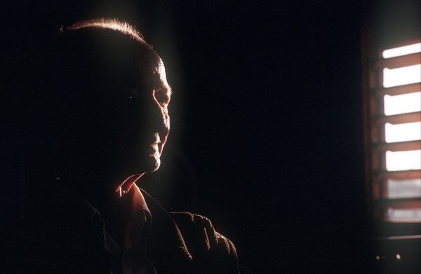 CUBA, Pinar del Rio, Portrait of an elderly farmer seen in a dark room with half of his face visible by light from a nearby shuttered window