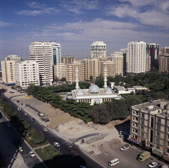 UAE, Abu Dhabi, Elevated view over mosque surrounded by trees and  high rise buildings near a road with traffic