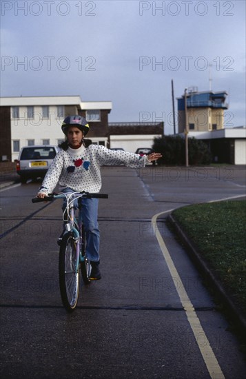 10013304 SPORT  Cyclists Girl wearing safety head gear  riding bike giving a hand signal.