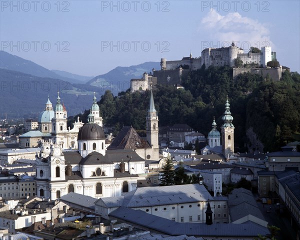 AUSTRIA, Salzburg Province, Salzburg, Hohensalzburg Fortress beyond town rooftops with wooded hills behind