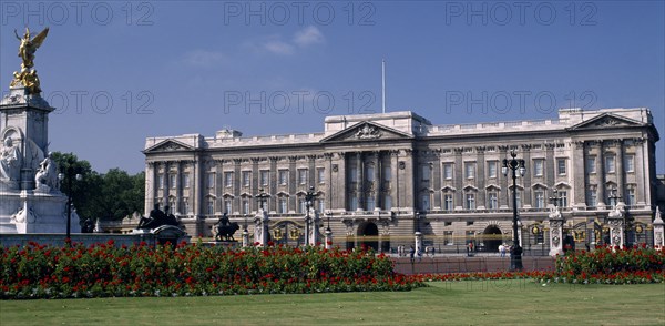 ENGLAND, London, Buckingham Palace.  Front view with the Victoria Memorial to the left and red flower beds and lawns