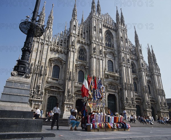 ITALY, Lombardy, Milan, Cathedral frontage with tourists  beside a souvenir stall selling flags and scarves