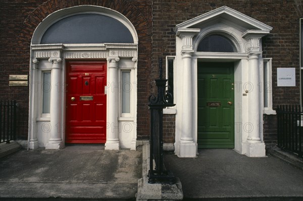 Ireland, Dublin, "Two Georgian front doors, one red and one green, separated by railings. Both with white columns and arches."