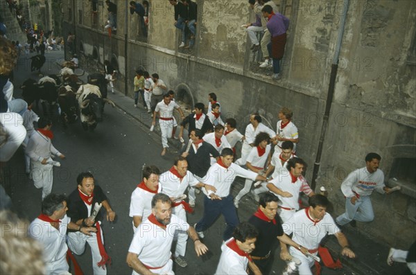SPAIN, Navarra, Pamplona, San Fermin Bull Run Festival people running ahead of bulls in narrow street