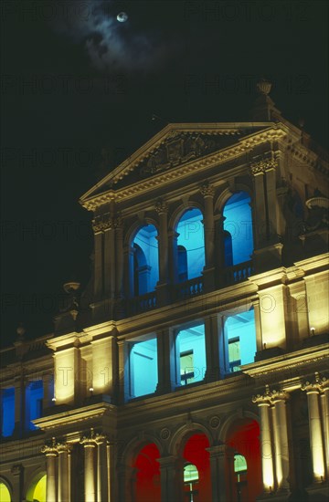 AUSTRALIA, Queensland, Brisbane, Treasury building facade with balconies lit in different colours at night.