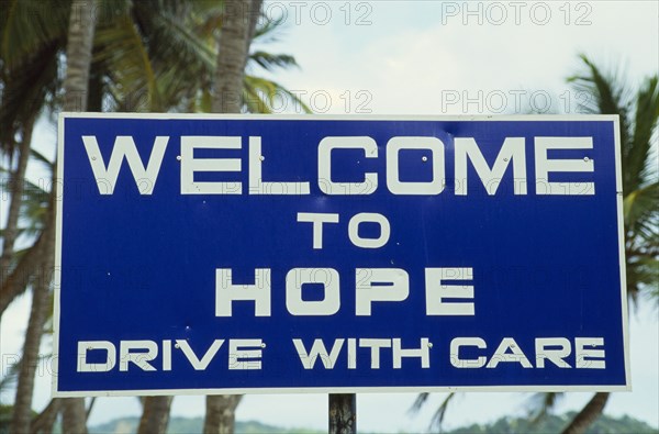 WEST INDIES, Tobago, Hope, Blue and white roadsign outside village reading Welcome To Hope Drive With Care