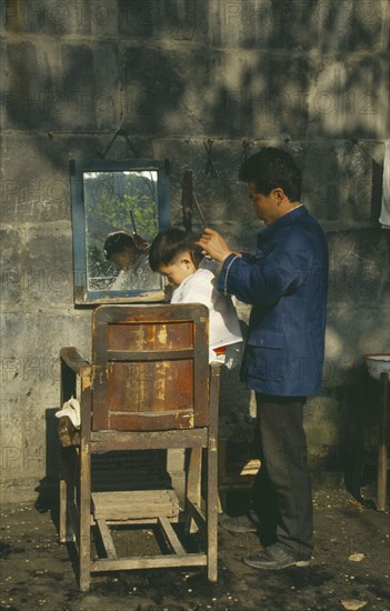 CHINA, Guanzhou, Barber cutting young boys hair