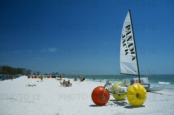 USA, Florida  , St.Petersburg, Hobbie cat and pedalo on stretch of white sand beach with few sunbathers.