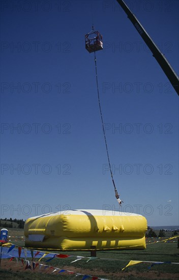 SPORT, Air, Bungee Jumping, Bungee jumper suspended from crane over inflated safety mat.