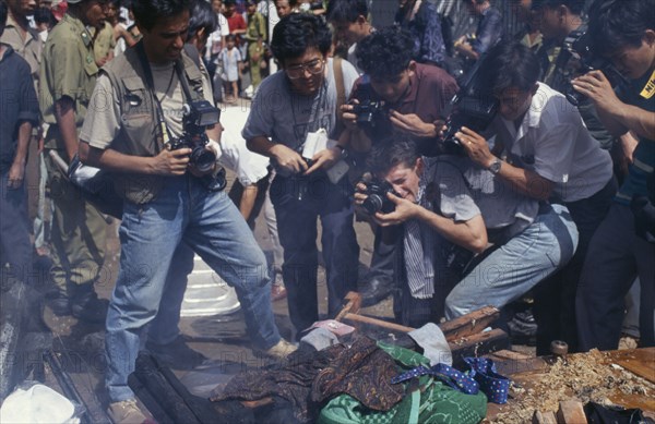 CAMBODIA, Phnom Penh, Press photographers taking close up photographs of a bonfire of the looted contents of the Khmer Rouge offices during an anti Khmer Rouge demonstration