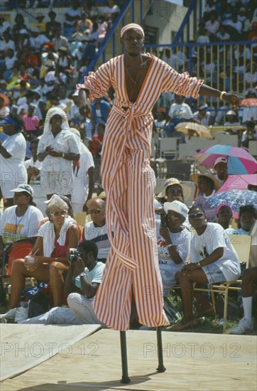 WEST INDIES, Barbados, Crop Over, Stiltman in pink and white at traditional harvest festival to celebrate bringing in the sugar cane crop