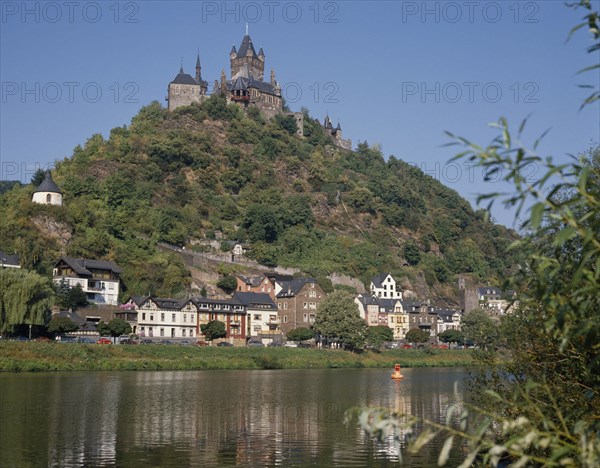 GERMANY, Rhineland, Cochem, Hilltop castle with conical towers overlooking houses beside the Mosel River