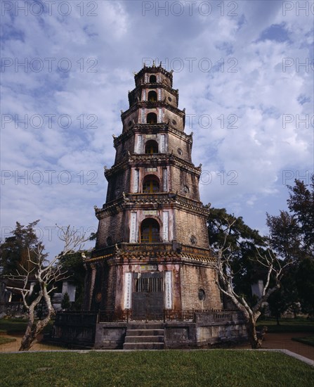 VIETNAM, Central, Hue, "Thien Mu Pagoda,tiered brickwork,trees & dead trunks,mottled sky "