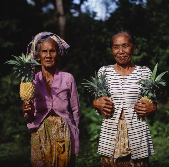 INDONESIA, Lombok, Batu Layar, Two ladies near Senggigi holding pineapples