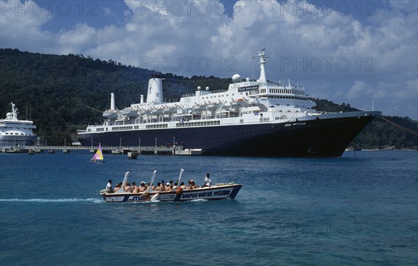 WEST INDIES, Jamaica, Ocho Rios, Tourist boat full of passegers passing cruise ship moored in harbour.