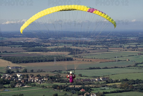 10037037 SPORT Air Paragliding Paraglider with yellow chute and landscape below.