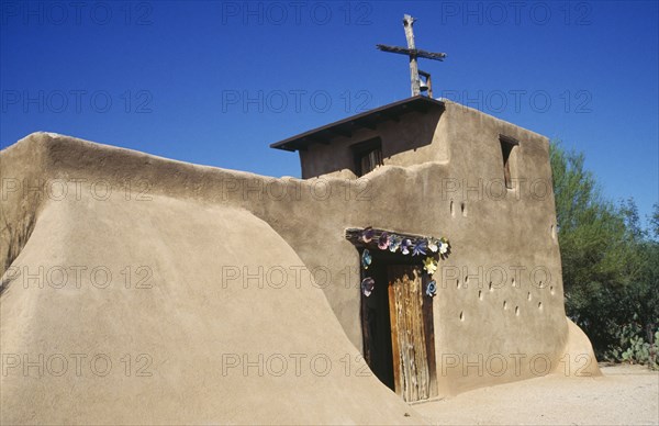 USA, Arizona, Tucson, De Grazias Mission church exterior with plain sandstone walls and floral decoration around the doorway.