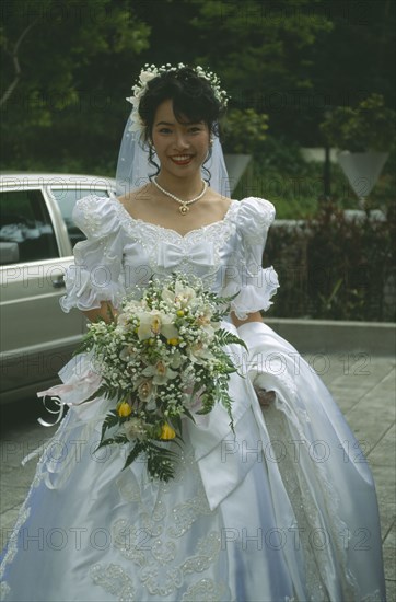HONG KONG, Central, Hong Kong Park, Bride at registry office dressed in traditional western style white dress with veil and bouquet  of orchids.
