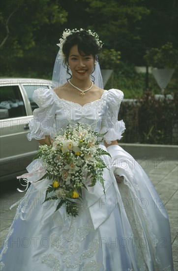 HONG KONG, Central, Hong Kong Park, Bride at registry office dressed in traditional western style white dress with veil and bouquet of orchids.