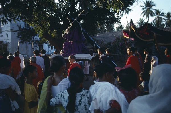 INDIA, Goa, Margao, Easter Procession.  Men carrying statue of Christ at calvary through street and watching crowd.