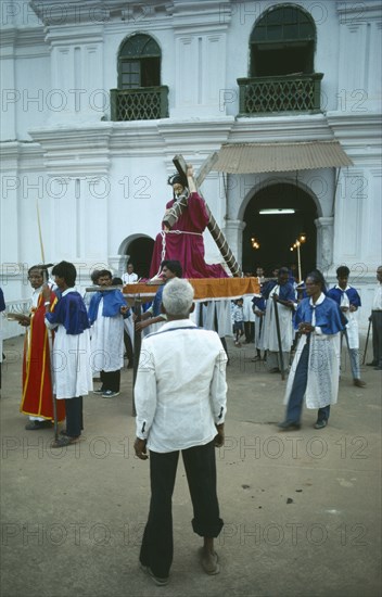 INDIA, Goa, Easter , Procession outside village church with statue of Christ being carried out of church watched by shoeless old man