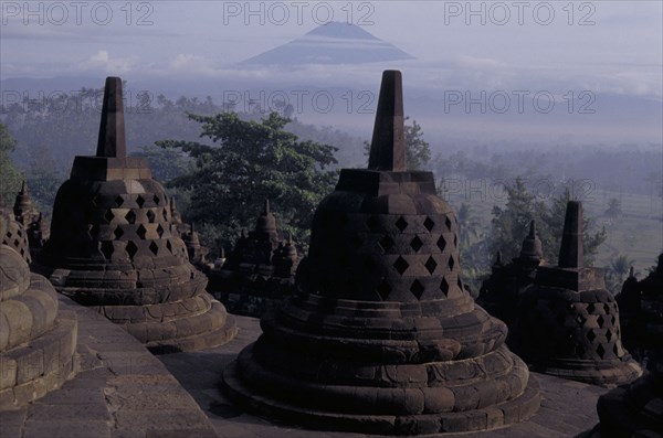 INDONESIA, Java, Borabudur, Part of the temple showing bell shaped structures at dawn