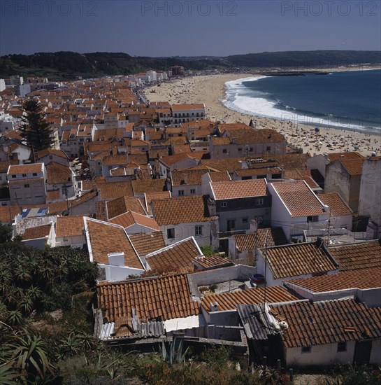 PORTUGAL, Estremadura, Nazara, View over main beach and town roof tops with mountains behind