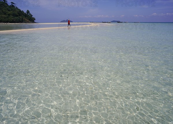 THAILAND, Krabi, Phi Phi Don, Lobagao Bay on the north coast of the island with a man in red walking along a sand bar