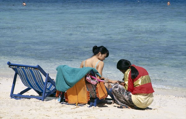 THAILAND, Phuket, Koh Hi, Also known as Coral Island. Japanese tourist sitting in a deck chair on the beach having a manicure
