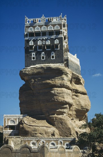 YEMEN, Wadi Dhar, Palace of the Rock, View looking up at grey and white building perched on top of  rock.