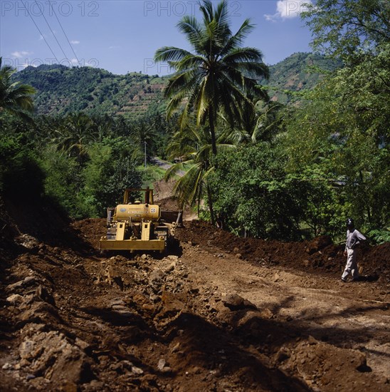 INDONESIA, Lombok, Senggigi, "Bansal road repairing after heavy rain using Caterpillar bulldozer, tarmac road coconut palm, trees & terraced fields behind. Lombok Barat, NTB J 6574 "