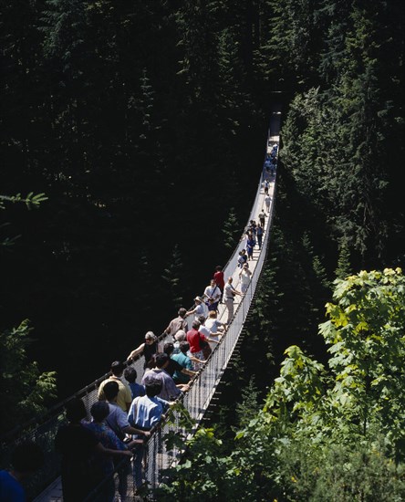 CANADA, British Columbia, Vancouver, Capilano Suspension Bridge with tourists crossing the tree lined gorge