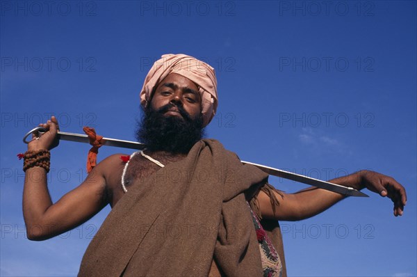 INDIA, Delhi , SIkh man holding Holy Kirpan Sword for the defence of the weak.  Three-quarter view looking up from below.