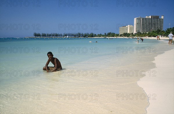 WEST INDIES, Jamaica , Ocho Rios , Sunbather on the beach with hotel behind