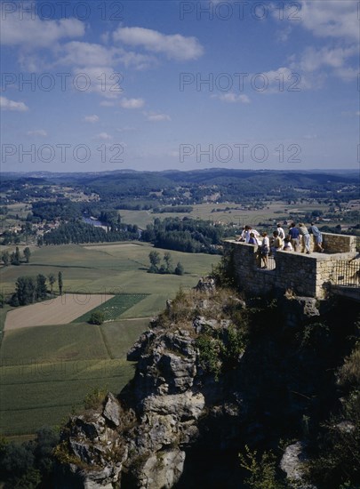 FRANCE, Aquitaine, Dordogne , Domme. People standing on a brick platform on a rocky hill looking over the green landscape.
