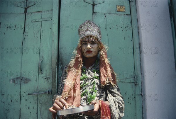 INDIA, Rajasthan, Udaipur , "Hermaphrodite with painted face and head-dress.  Ambiguous male features.  Subject of Indian myth, referred to as Hijras and often work as street performers."