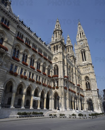 AUSTRIA, Lower Austria, Vienna, City Hall a stone facade with tall spires and red flowers in window boxes