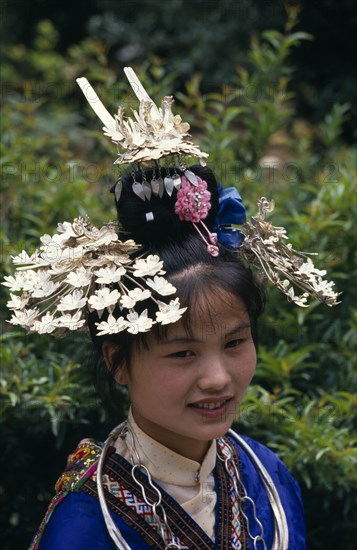 CHINA, Guizhou Province, Kaili , Miao girl in traditional costume and headress with silver decoration.  Head and shoulders portrait.