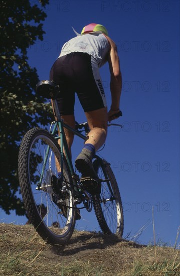 10067512 SPORT Cycling  Mountain Biking Mountain biker on crest of hill seen from behind.