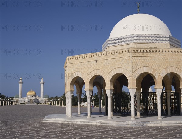 TUNISIA, Monastir, Bourguiba Mausoleum in distance beyond an arched portico with a white dome