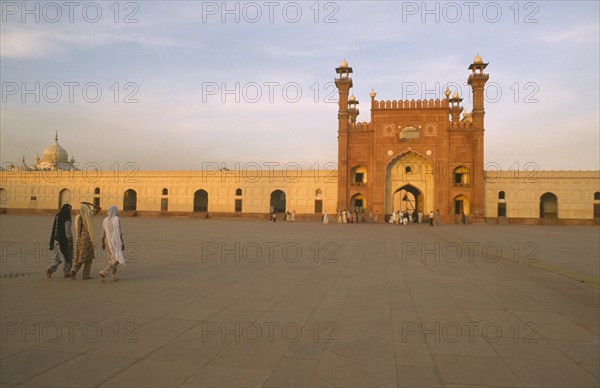 PAKISTAN, Punjab, Lahore , Badshahi Mosque attached to the Royal Fort.  Built c.1672-3 during the reign of Mughal emperor Aurangzeb.  Visitors in courtyard in foreground.