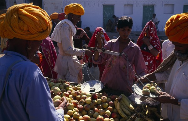 INDIA, Rajasthan , Pushkar , Vendor weighing apples for customer in fruit market.