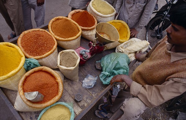 INDIA, Delhi , Looking down on stall in spice market with cropped view of male vendor and customers.