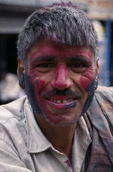 INDIA, Delhi, Head and shoulders portrait of man with face covered in pink and black coloured powderdye during Holi Festival.