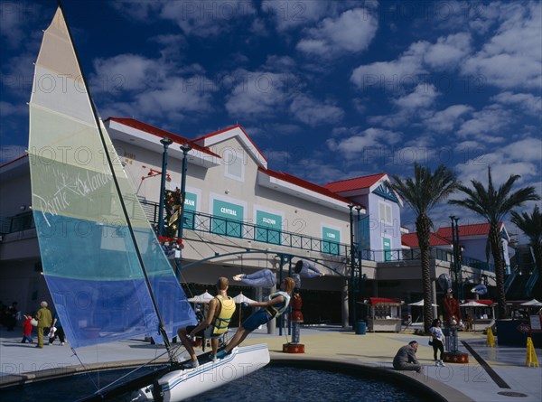 USA, Florida, Orlando, Pointe Orlando Shopping Complex with a sail boat display statue near visitors walking around colourful buildings
