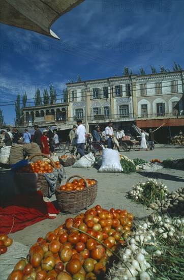 CHINA, Xinjiang, Kashgar, Vegetables for sale on the street in front of three storey buildings at the Sunday Market