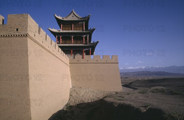 CHINA, Gansu , Jiayuguan Fort, View along turreted wall toward traditional building above and landscape below